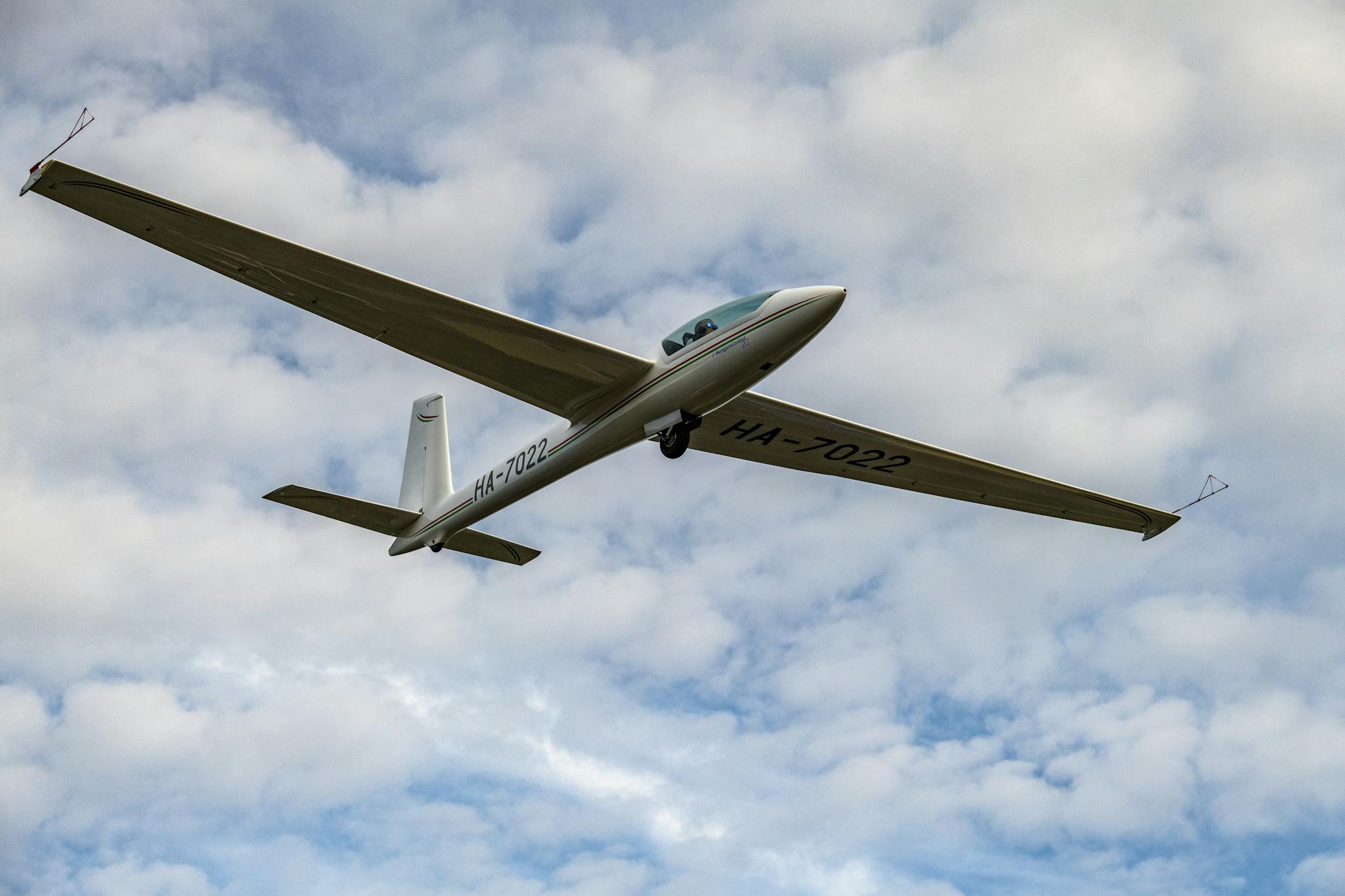A glider soaring gracefully through a partly cloudy sky, showcasing aerial beauty.