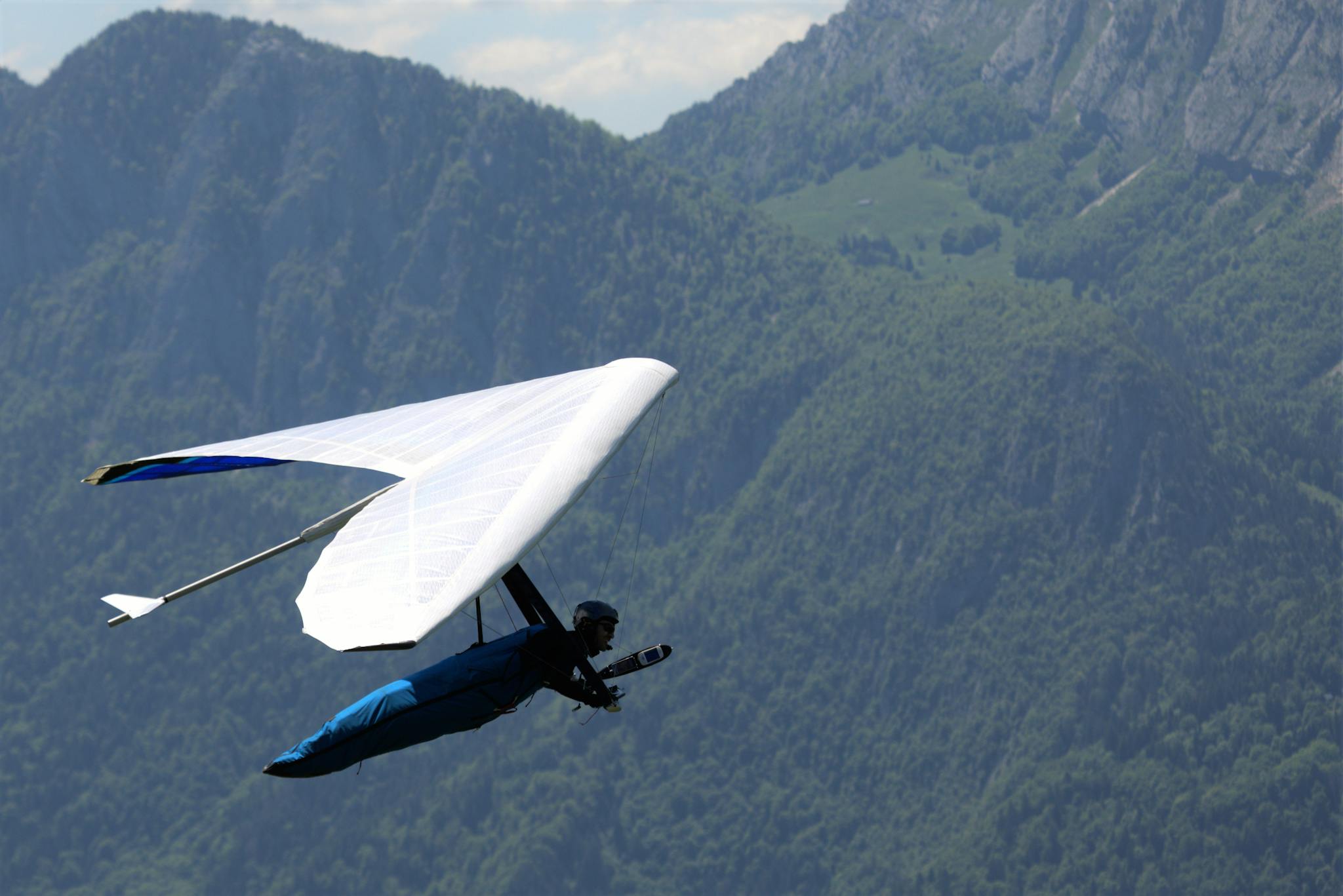 A hang glider flying over scenic mountains, capturing the thrill of adventure and freedom.