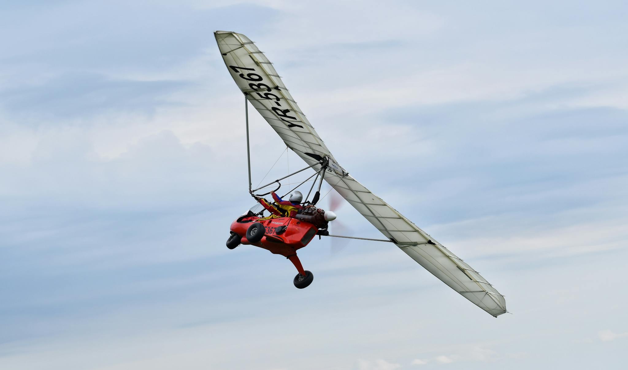 A vibrant ultralight aircraft soaring against an overcast sky, capturing the thrill of flight.